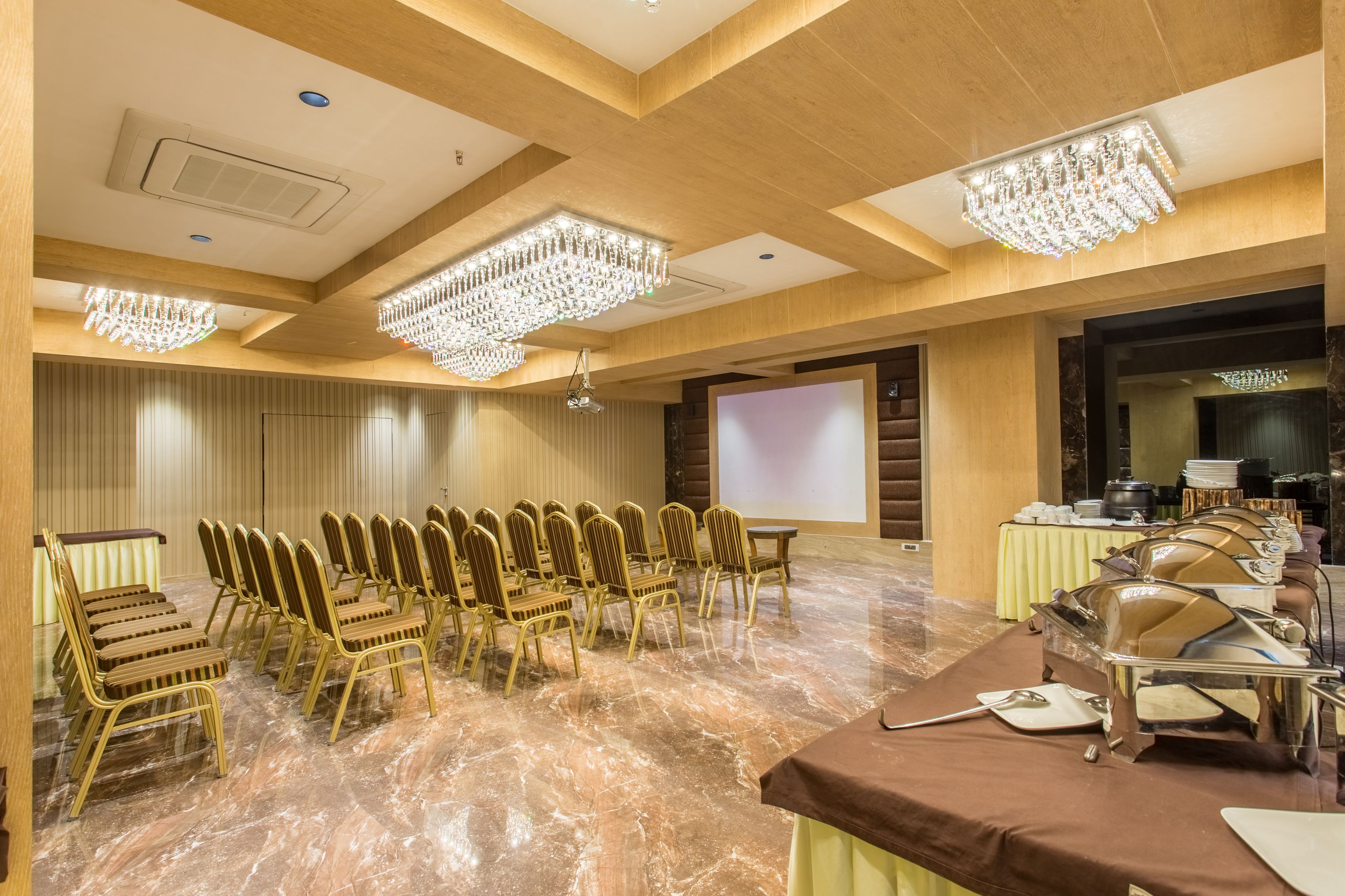 A conference room with rows of chairs, a projector screen, and buffet setup.
