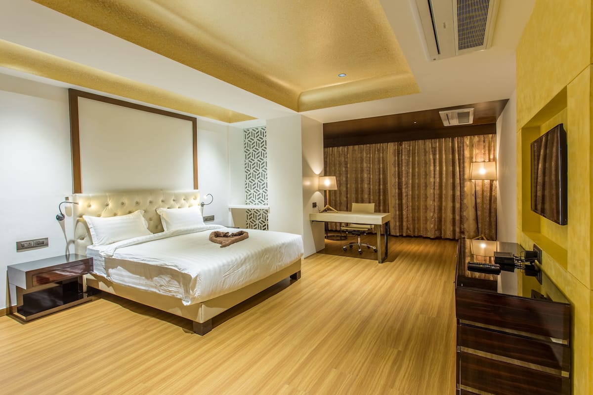 Una habitación de hotel moderna con una cama grande, mesita de noche, escritorio y silla.
