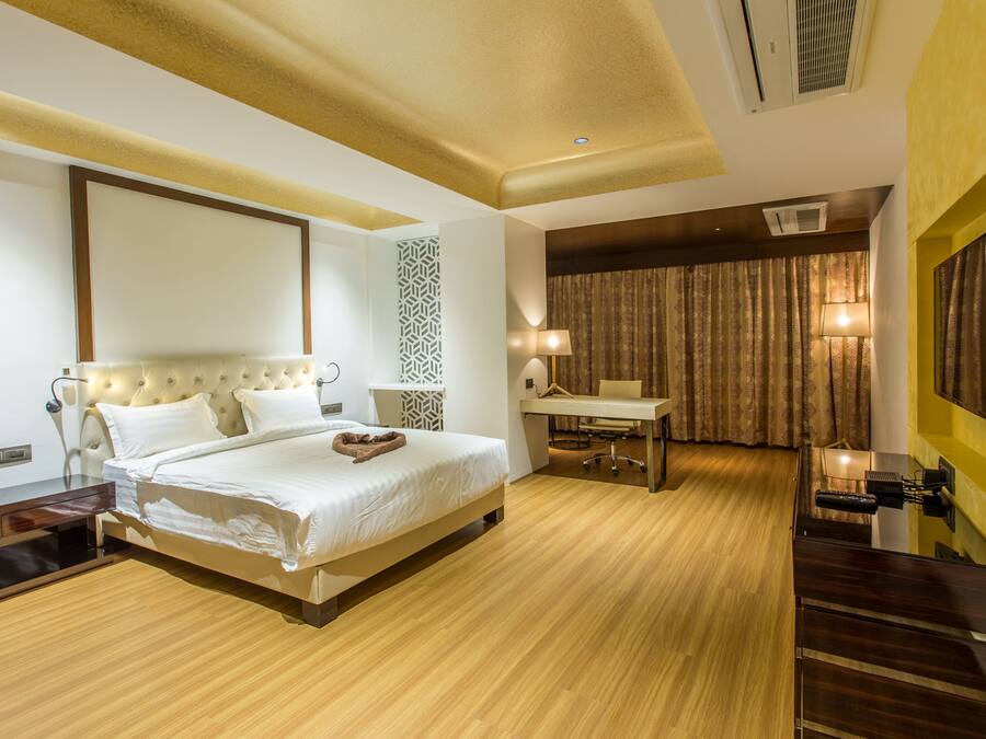 Una habitación de hotel moderna con una cama grande, mesita de noche, escritorio y silla.