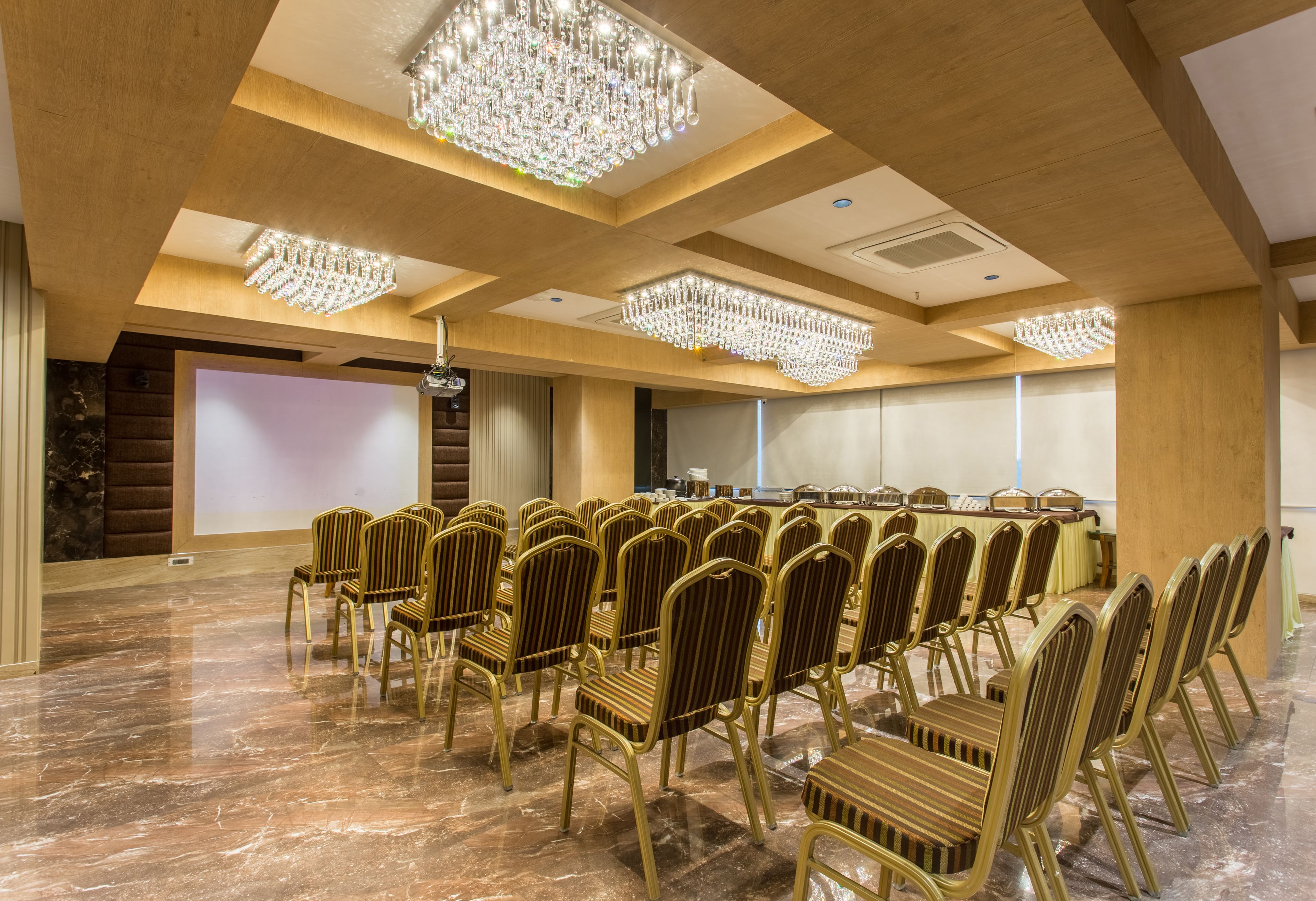 Una sala conferenze con file di sedie, un lungo tavolo e lampadari.