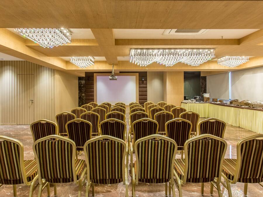 Ein Konferenzraum mit einem großen, ovalen Tisch, Reihen mit gestreiften Stühlen und Kronleuchtern.