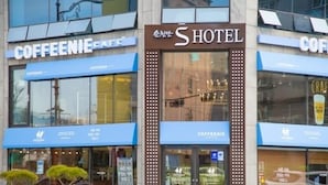 Et hotel med en moderne facade, store vinduer og skiltning for en café.