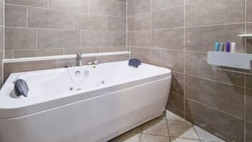 A modern bathroom with a freestanding bathtub, tiled walls, and a shower area.