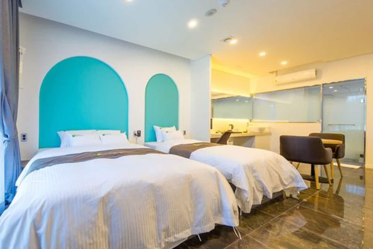 Ein Hotelzimmer mit zwei Betten, einem Schreibtisch und einem Stuhl.