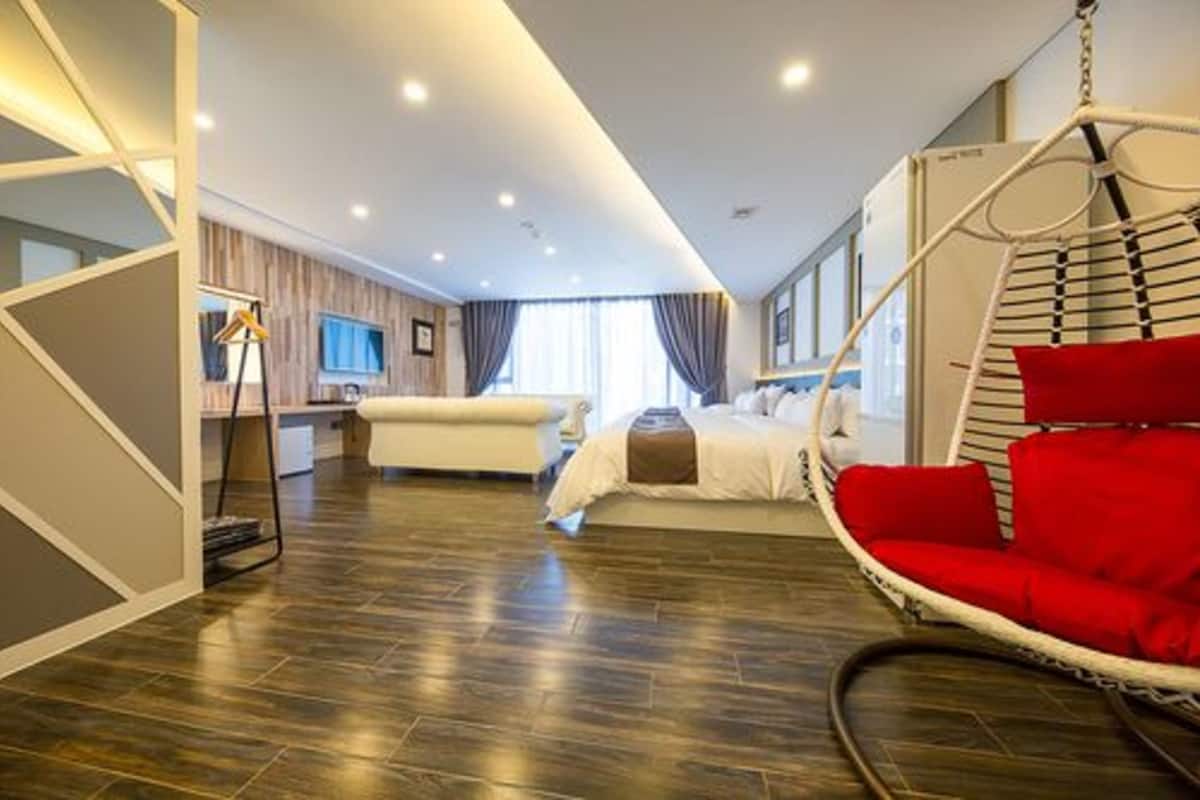 Ein modernes Hotelzimmer mit Hängekorbschaukel, Bett, Fernseher und Holzboden.