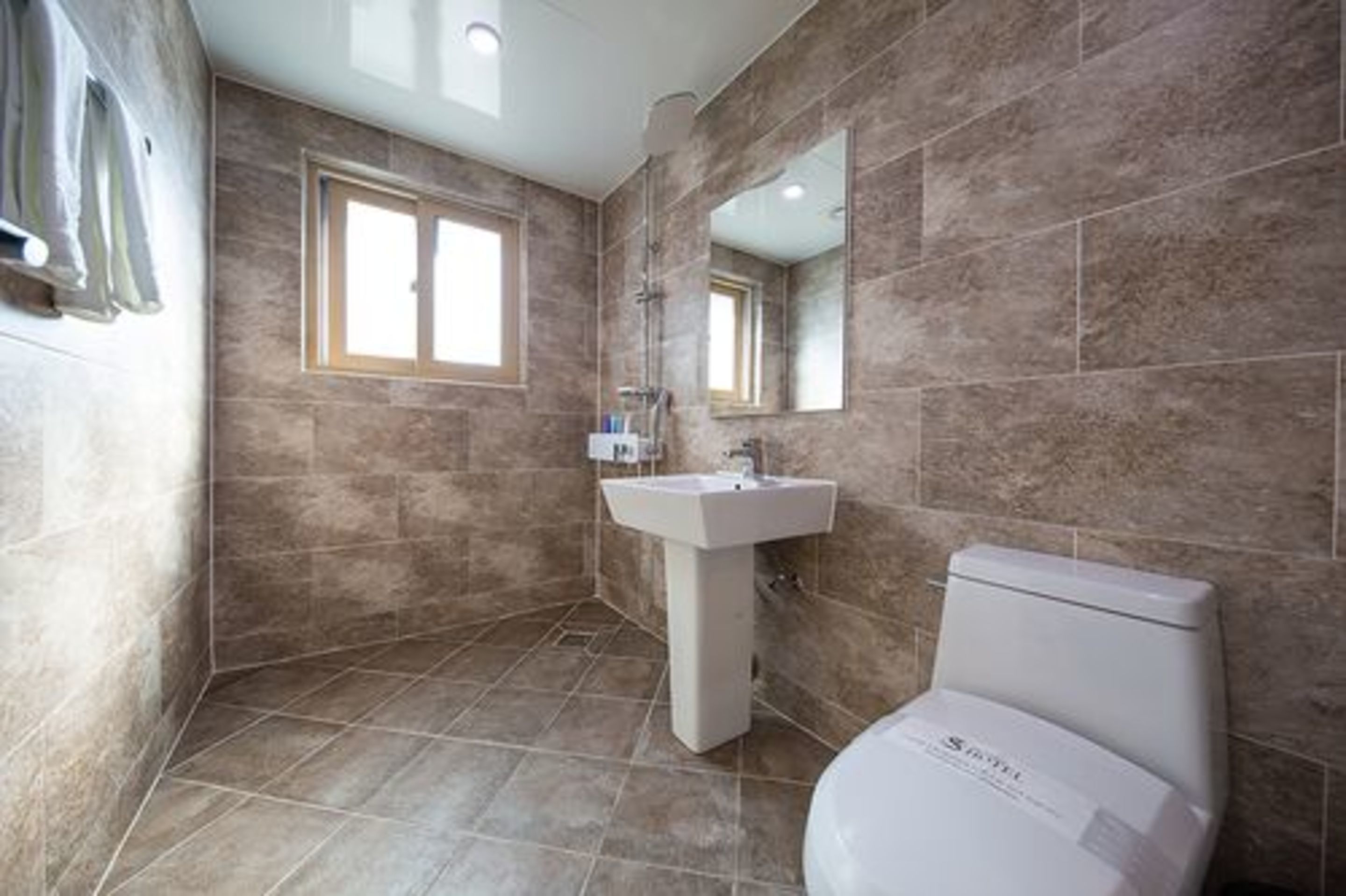 Un baño con una ventana grande, un lavamanos y un inodoro.