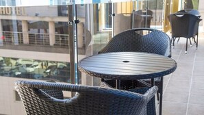 En balkon med fletningsmøbler og gelænder af glas.