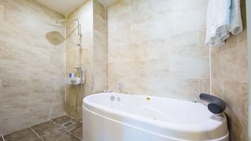 A modern bathroom with a freestanding bathtub, a showerhead, and a towel rack.