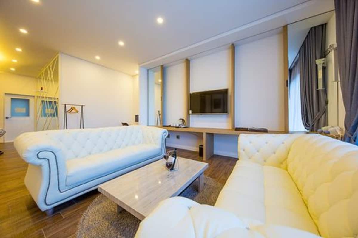 Ein modernes Wohnzimmer mit einem weißen Sofa, einem Couchtisch und einem flachbildfernseher an der Wand.