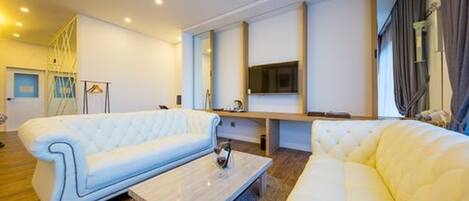 A modern living room with a white sofa, a coffee table, and a flat-screen TV mounted on the wall.
