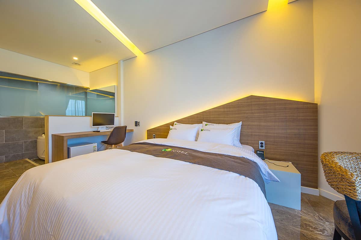 Ein modernes Hotelzimmer mit einem großen Bett, einem Schreibtisch und einem Stuhl.