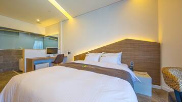 Una habitación de hotel moderna con una cama grande, un escritorio y una silla.