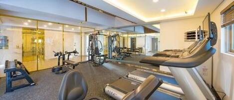 A modern gym with treadmills, weight machines, and a mirrored wall.