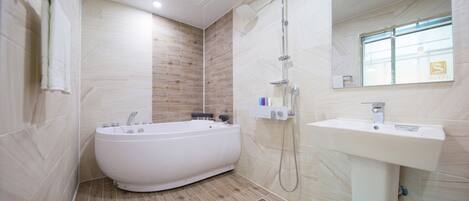 A modern bathroom with a bathtub, shower, and sink.