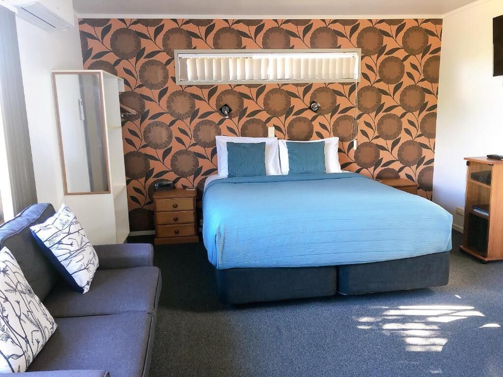 Un dormitorio con cama, cómoda, espejo y pared con diseño.