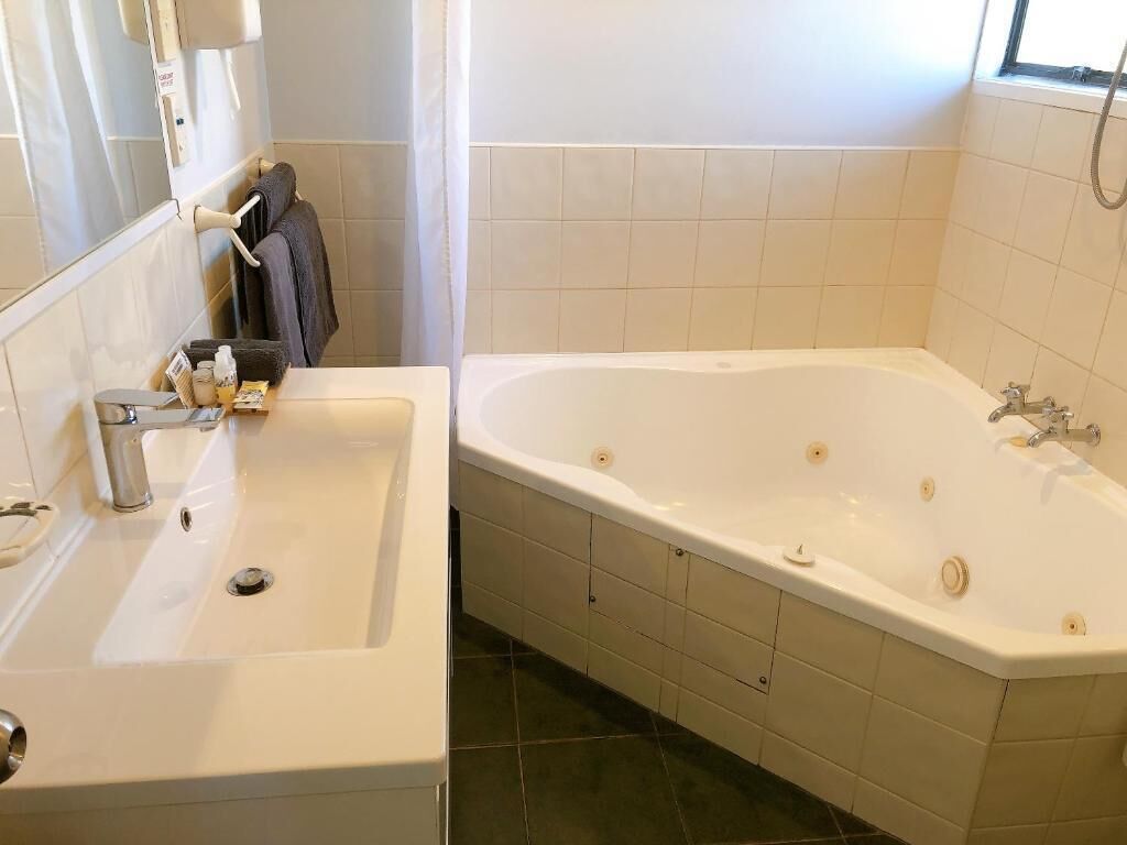A bathroom with a white sink, a bathtub, and a towel rack.