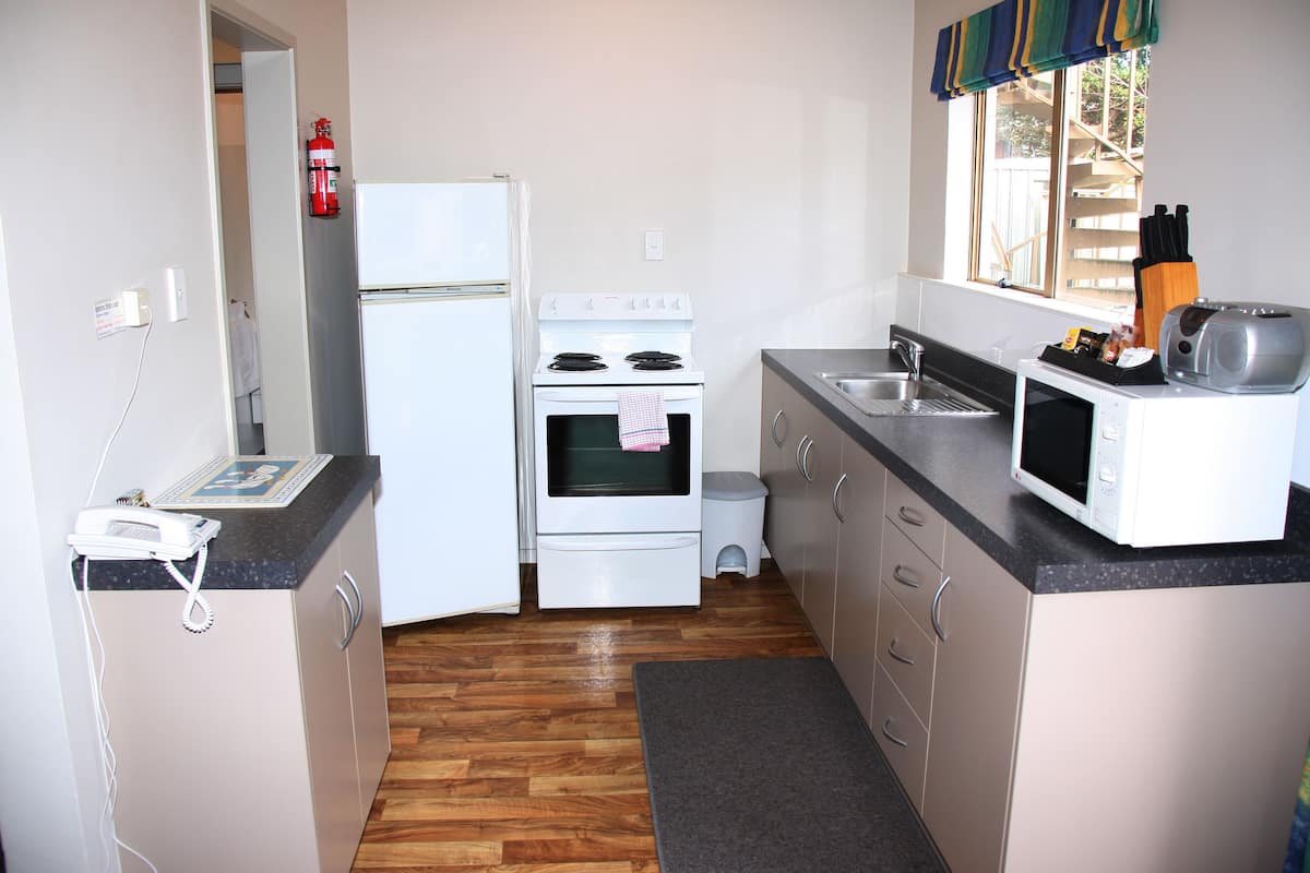 A compact kitchen with a refrigerator, stove, microwave, and sink.
