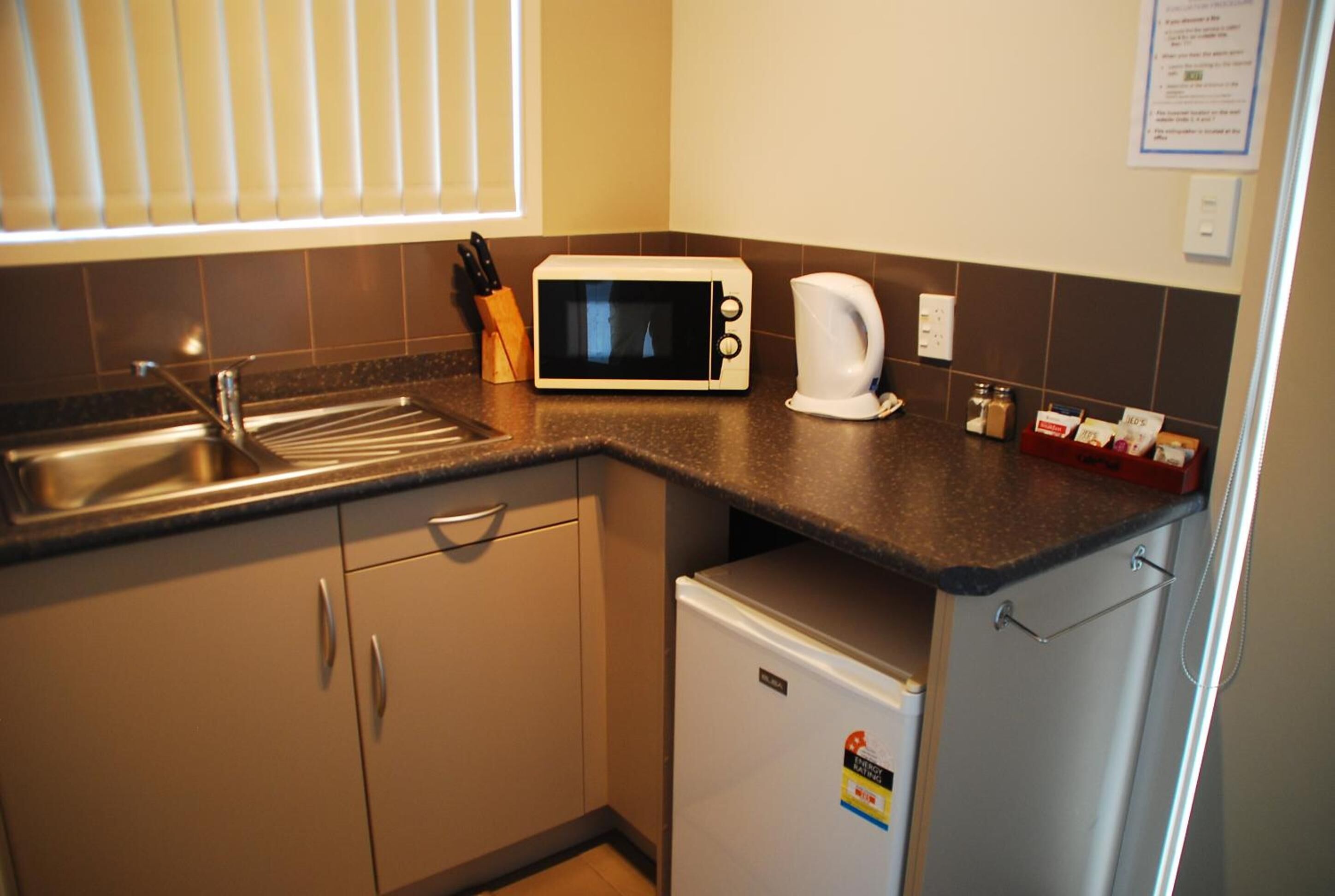 A compact kitchen with a microwave, kettle, and a small refrigerator.
