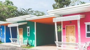 A row of colorful cabins with white railings and doors, each with a small porch area.