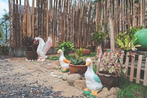 Un giardino con statue decorative a forma di cigno, piante in vaso e una recinzione in legno.
