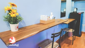 A reception desk with a potted plant, a wooden counter, and a seating area with chairs.