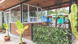 A covered outdoor area with brick walls, large windows, and potted plants.