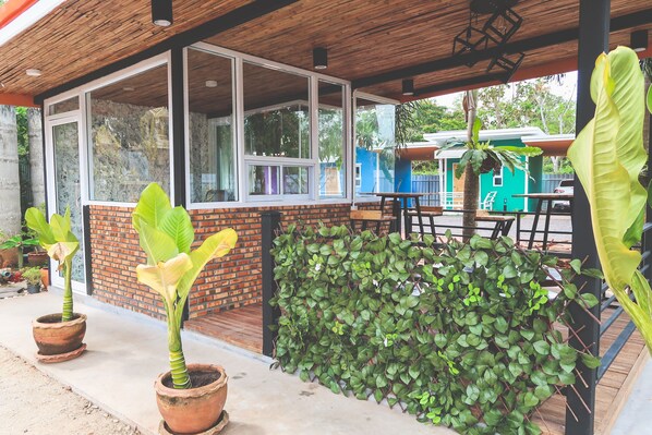 A covered outdoor area with brick walls, large windows, and potted plants.