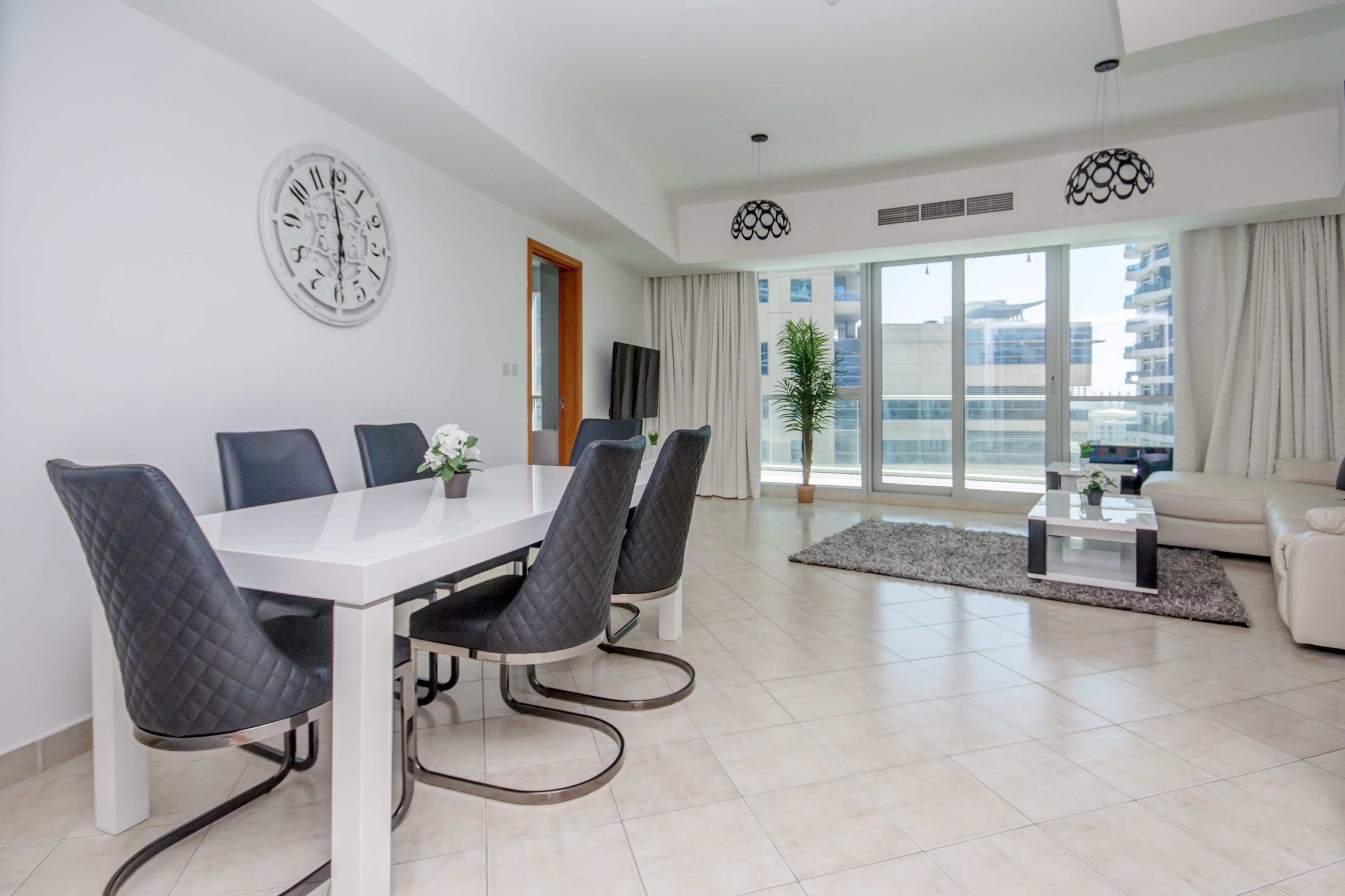 A modern living room with a dining area, large windows, and a view of the city.