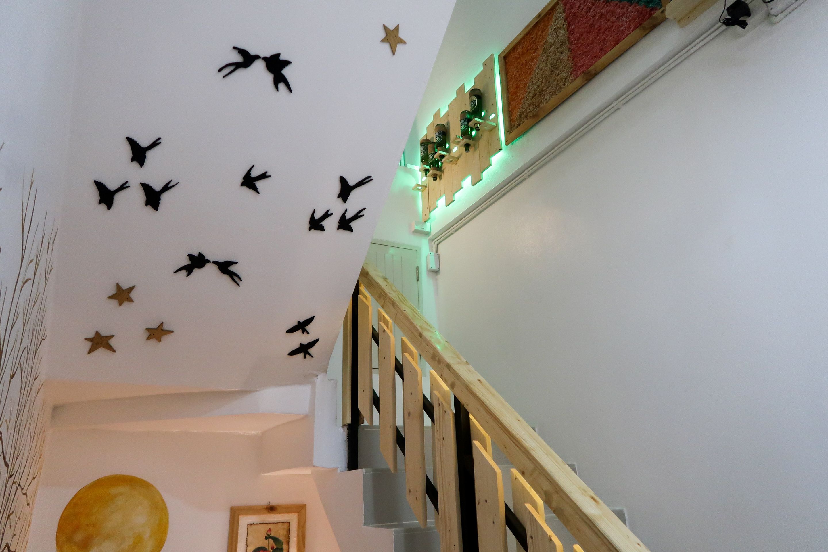 A staircase with wooden railings and a wall decorated with black silhouettes of birds and stars.