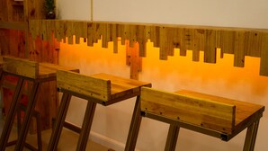 A row of wooden benches with a unique backrest design against a wall. - Baan URT Suratthani Airport Hotel (Phunphin)