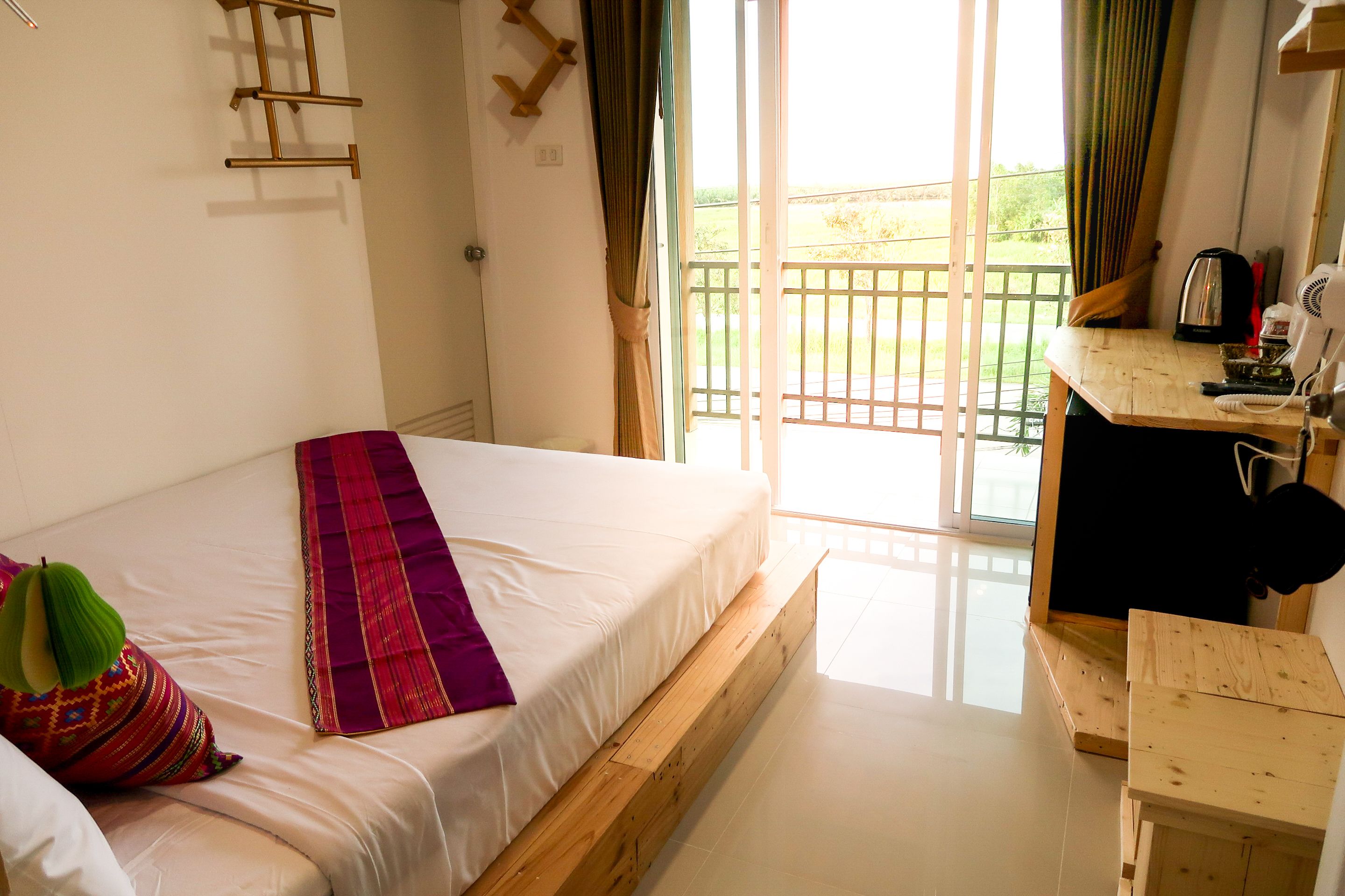 A bedroom with a bed, a wooden desk, and a view of the outdoors.