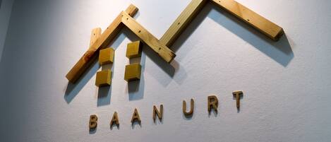 A wooden sign with the text "BAAN URT" on a white wall.