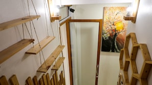 A room with a wooden slat wall, a glass door, and a painting of a tree with a full moon. - Baan URT Suratthani Airport Hotel (Phunphin)