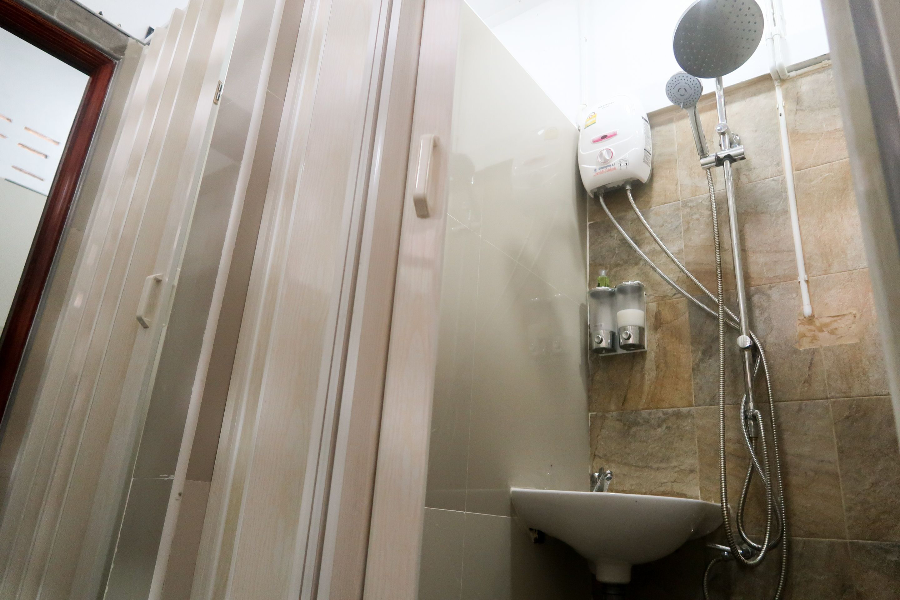 A bathroom with a shower, a sink, and a hairdryer on the wall.