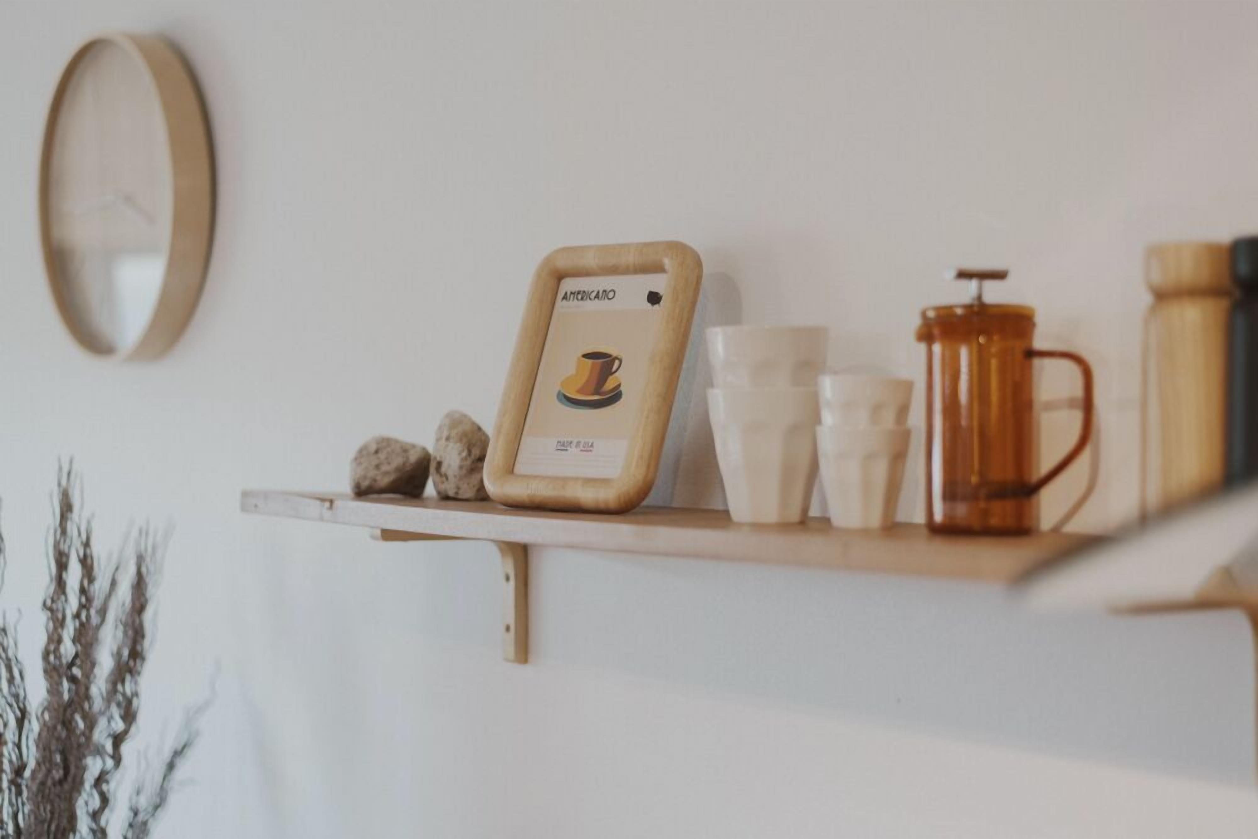 Una estant amb un molinillo de cafè, tasses i un menú emmarcat.