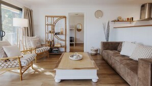 Un salón espacioso con una mesa de centro de madera, un sofá marrón y un sofá de mimbre.