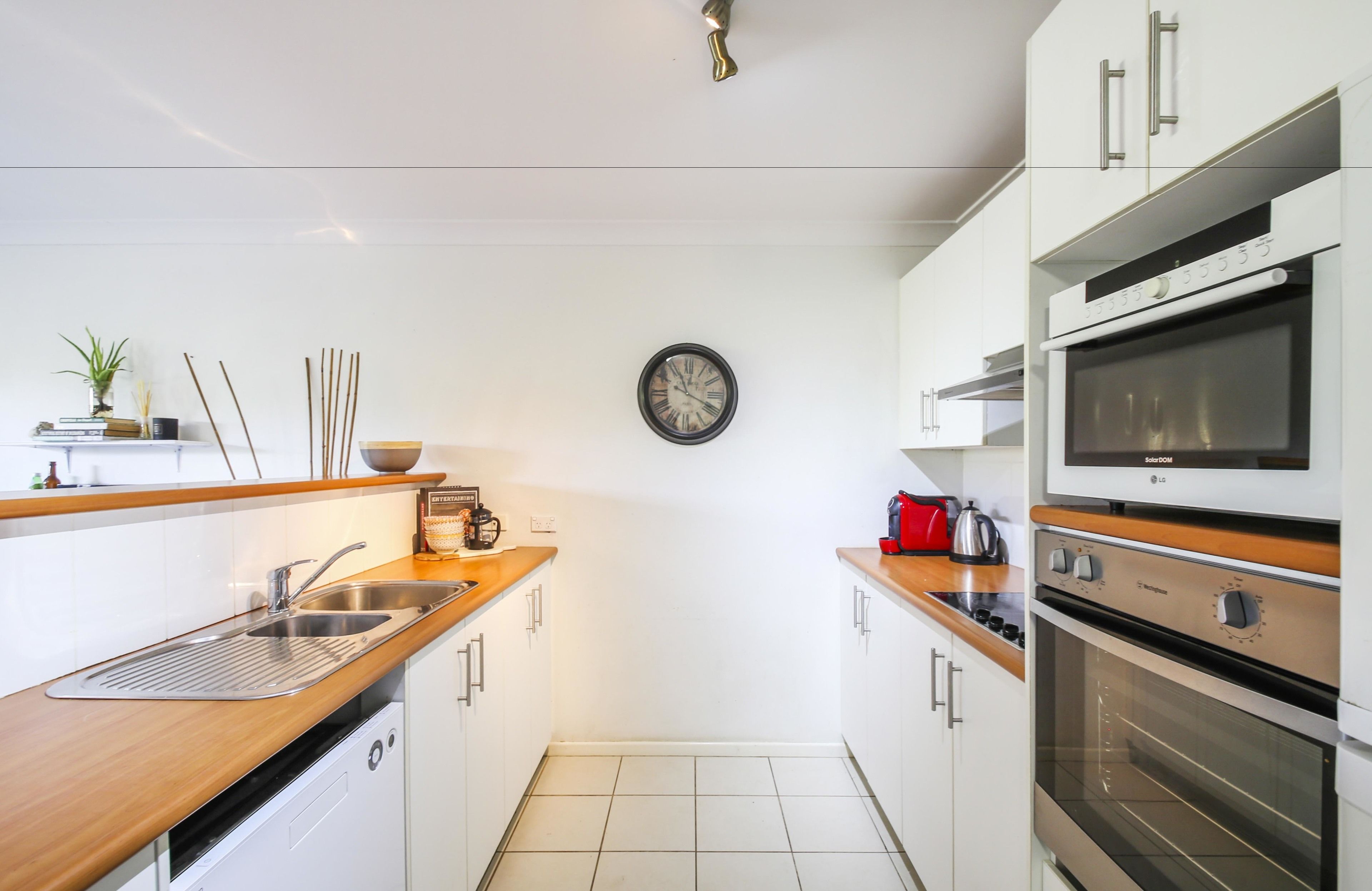 A modern kitchen with white cabinets, stainless steel appliances, and a wooden countertop.