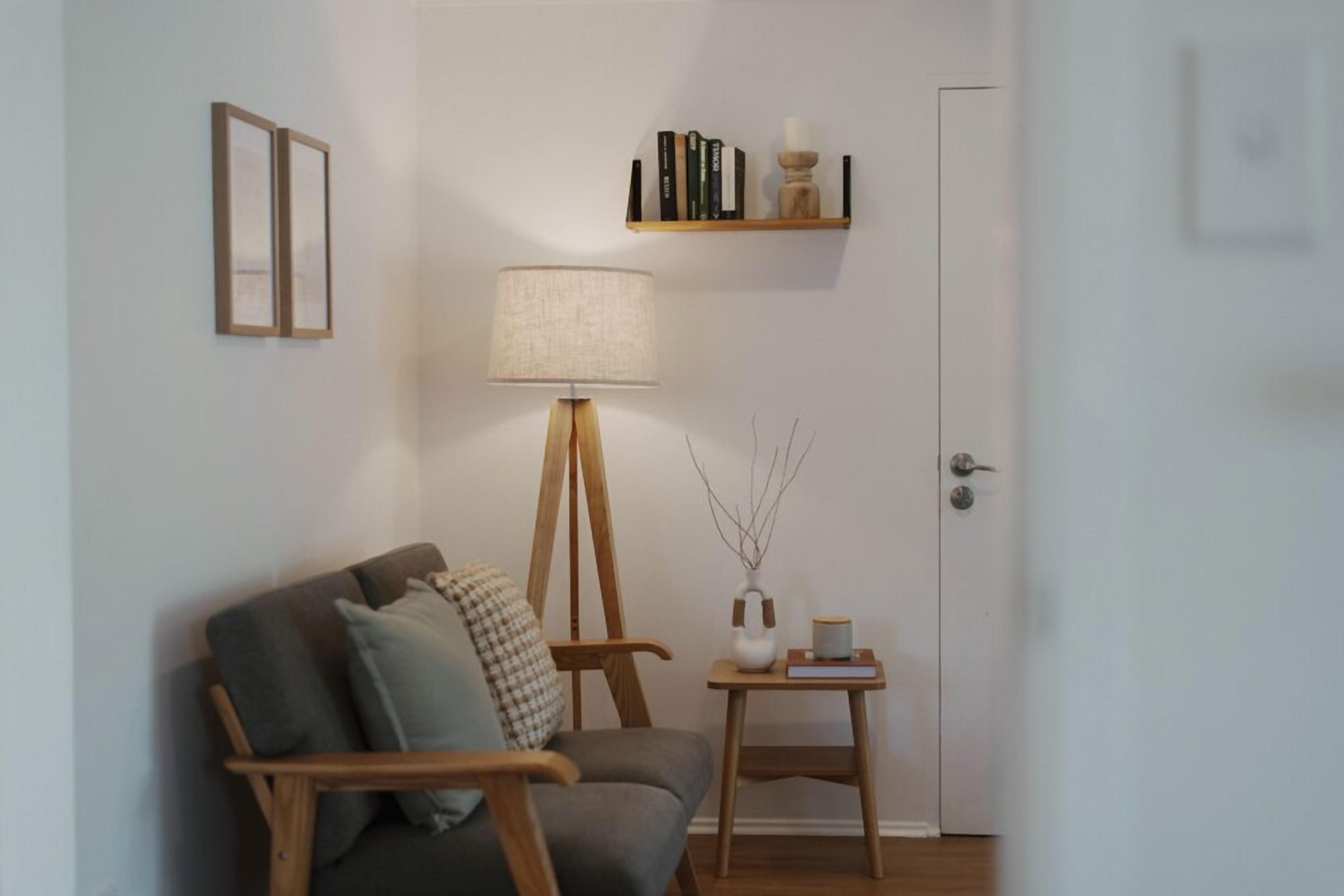 A living room with a sofa, a floor lamp, a small side table, and a bookshelf.