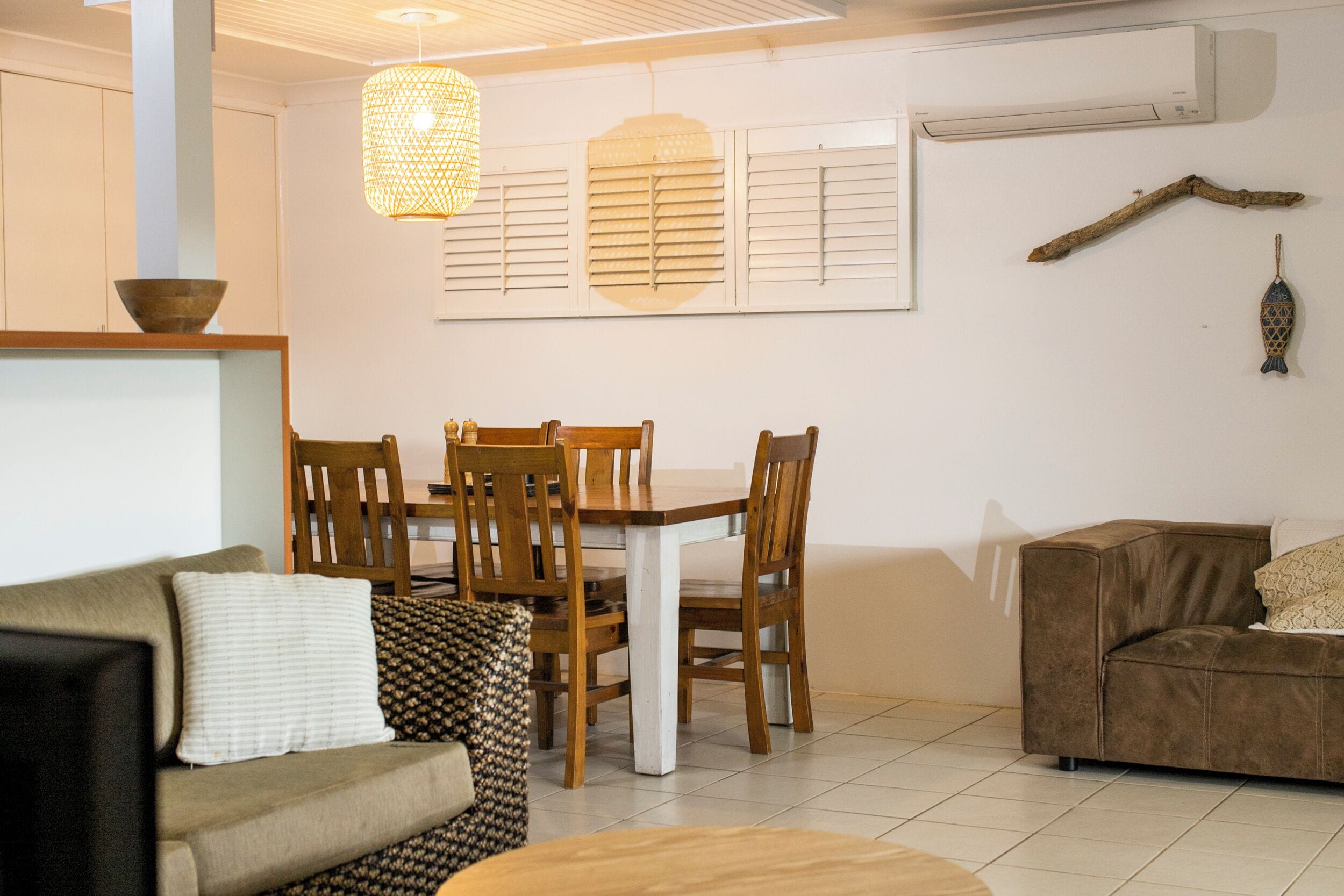 A dining area with a wooden table and chairs, a sofa, and a brown couch.