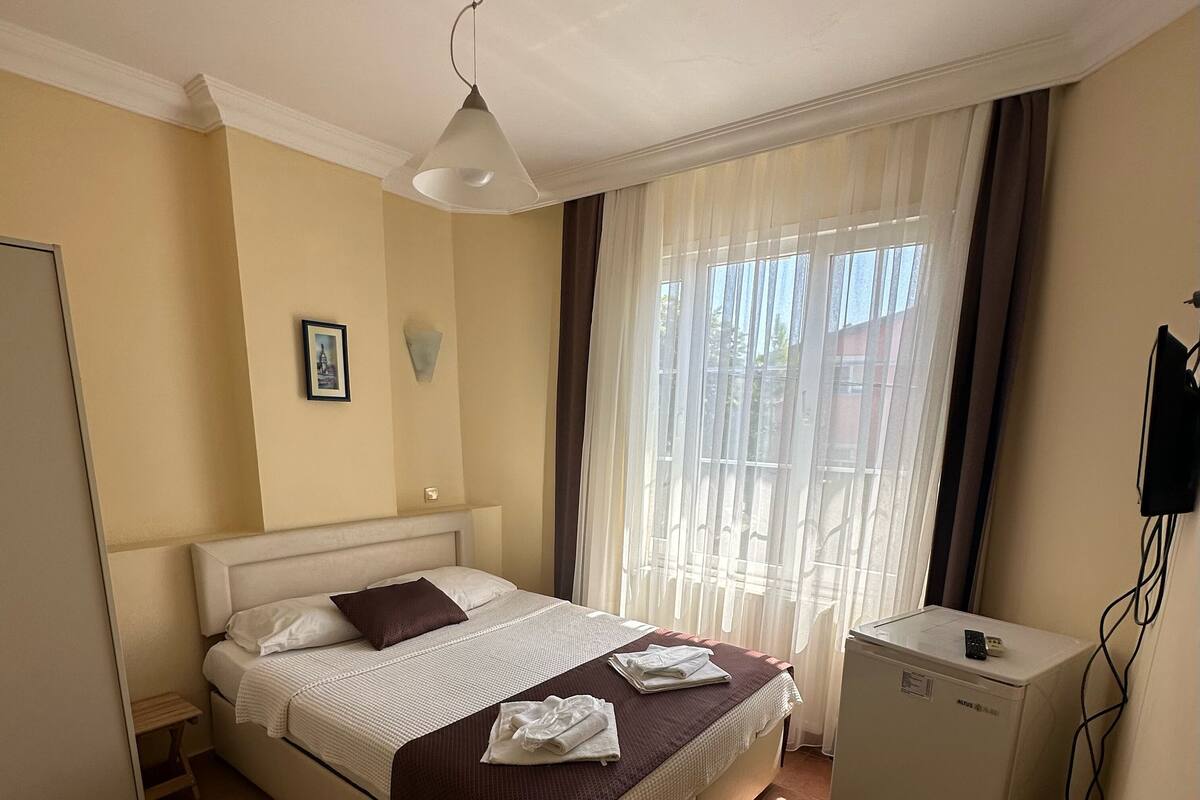 A neatly arranged bedroom with a bed, bedside table, and a small refrigerator.
