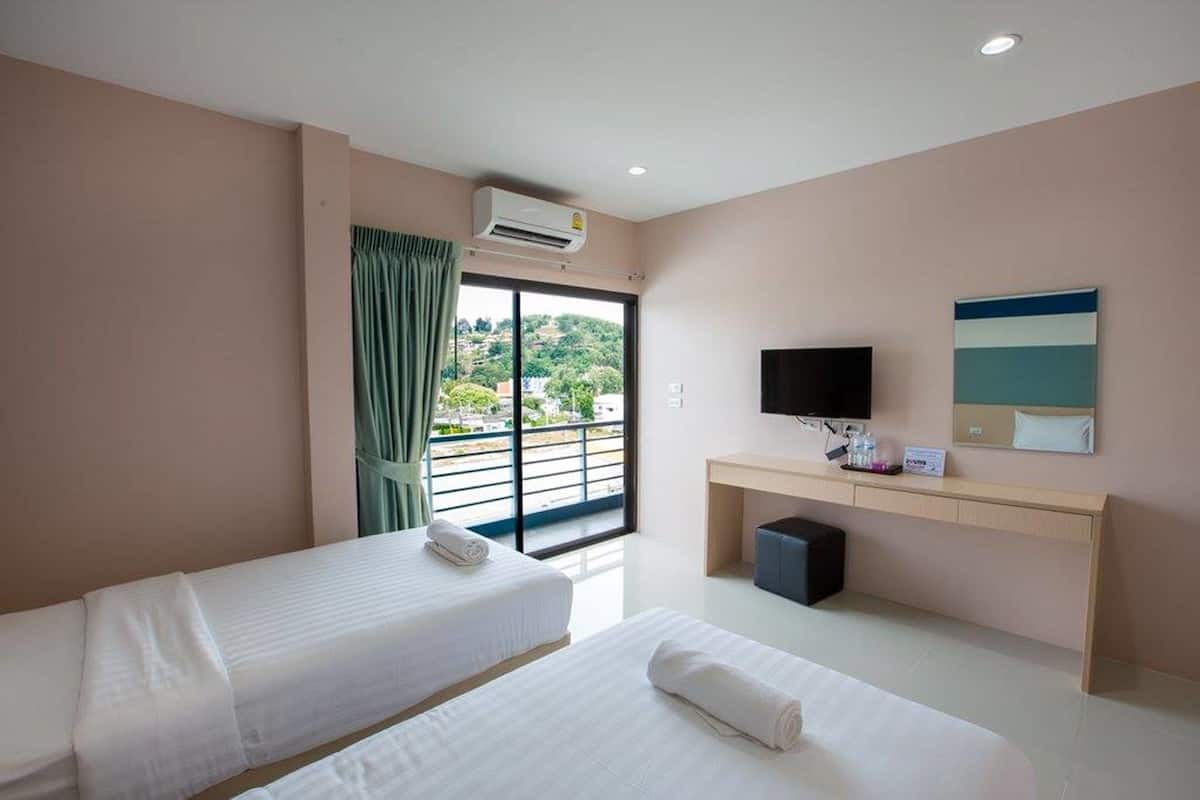 Habitación de hotel con dos camas, televisión, escritorio y ventana con vistas.