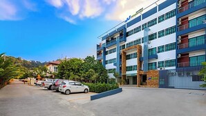 Un hotel de varios pisos con un diseño moderno, que cuenta con un patio central con coches aparcados.