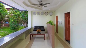 Zona de recepción con un sofá, una mesa de centro con flores, un reloj y un ventilador de techo.