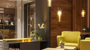 A modern interior with a sofa, a wooden coffee table, and a fireplace with logs. - Hotel Eden No. 7 (Saas-Fee)