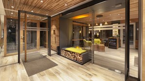 A modern interior with a wooden ceiling, glass walls, a seating area with a fire feature, and a visible bar area. - Hotel Eden No. 7 (Saas-Fee)
