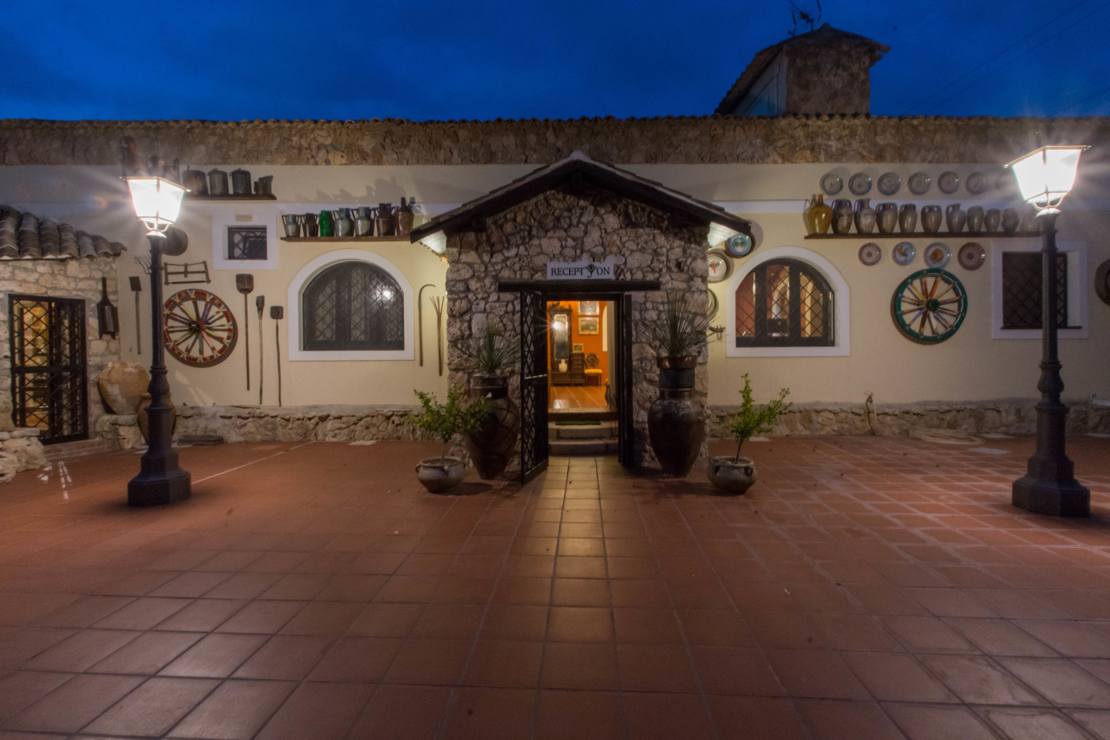 A stone building with a sign reading "RECEPTION" at the entrance, surrounded by potted plants and street lamps.