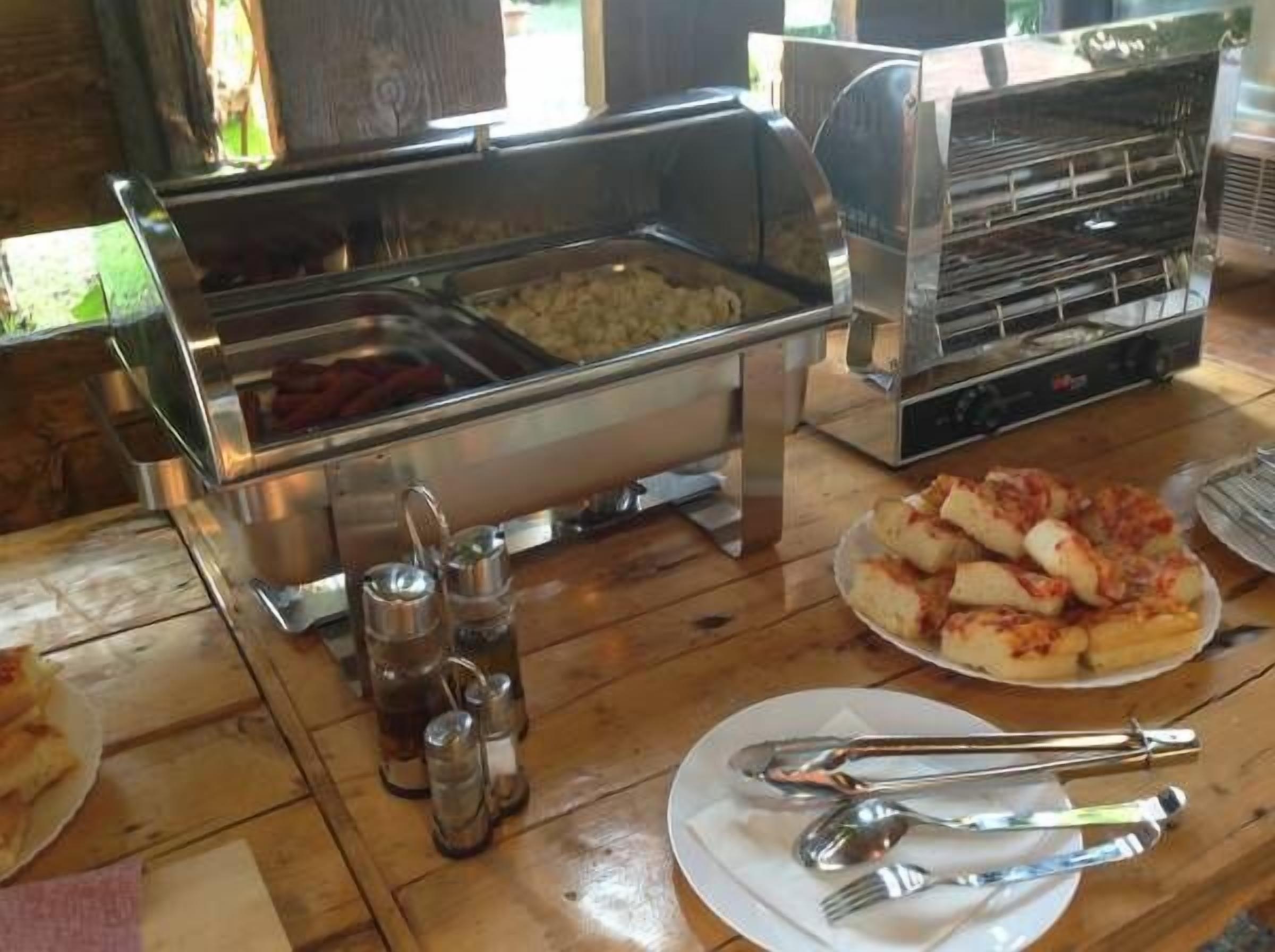 Una mesa de madera con diversos alimentos y utensilios para un servicio de buffet.