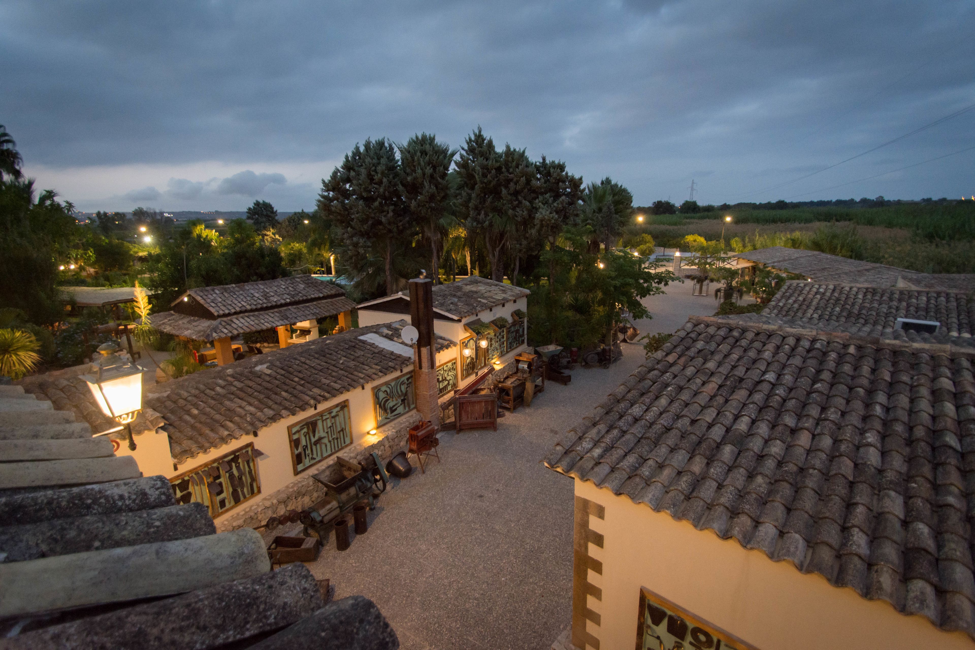 A courtyard with traditional tiled roofs, outdoor seating, and a view of the surrounding landscape.