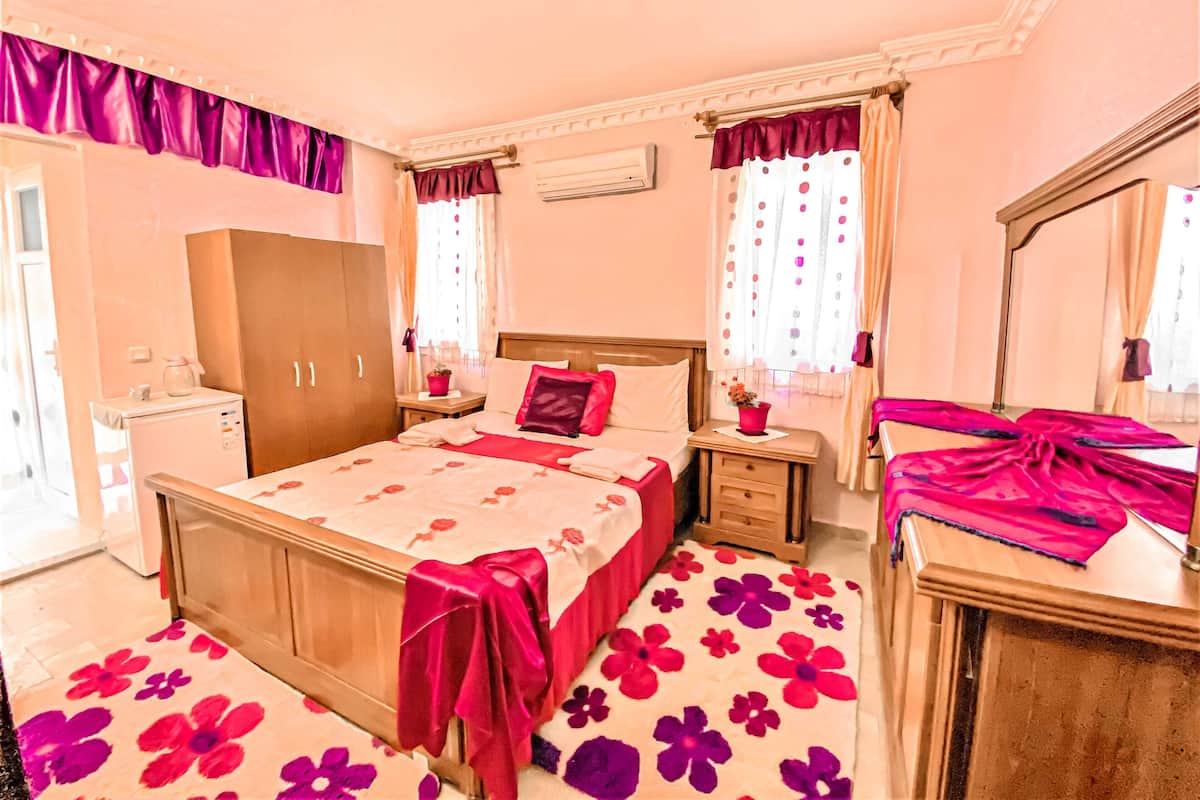 A bedroom with a bed, nightstands, a dresser, a wardrobe, and a mirror.