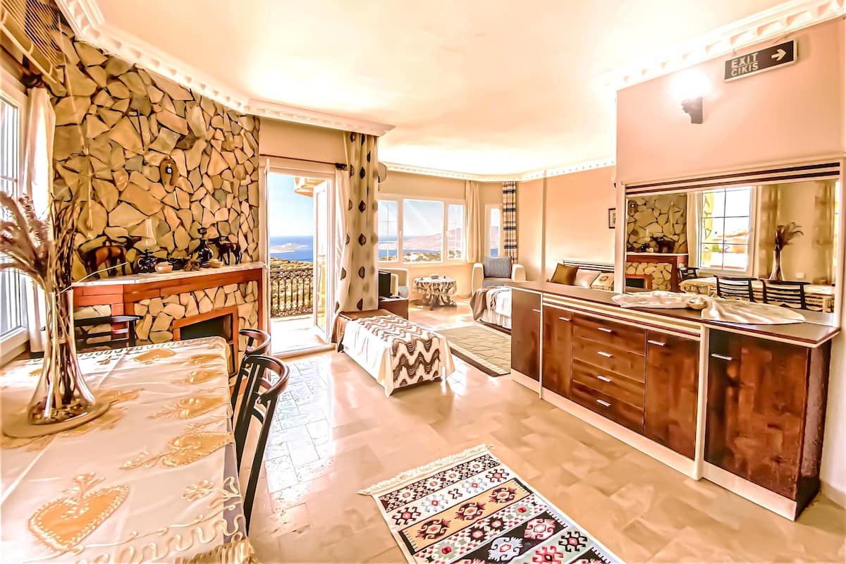 A spacious living room with a stone wall, a dining area, and a view of the sea.